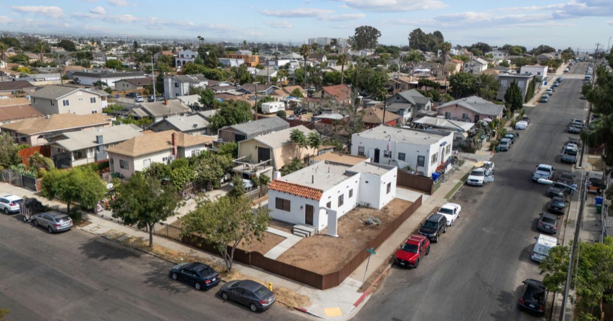 Aerial view of a single-story San Diego home mid-renovation with new fence and bare front yard — example of a distressed property