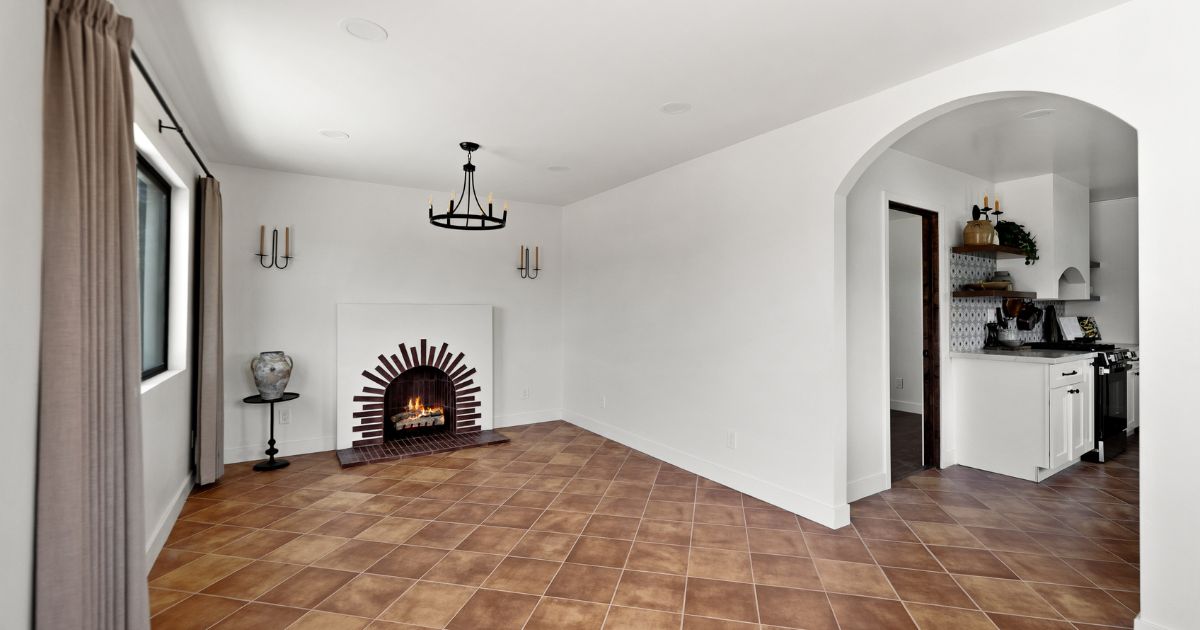 Bright staged San Diego living room with arched brick fireplace and open kitchen — example of a co-owned home professionally prepped for sale by Lovery Real Estate.