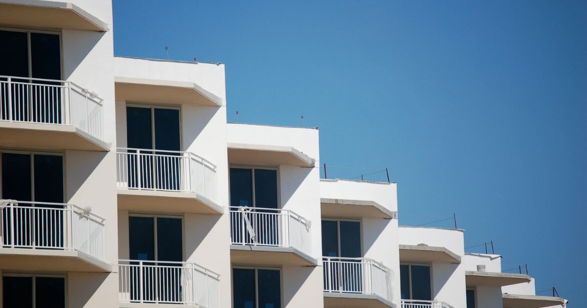 Modern white condominium building with balconies against a clear blue sky, representing San Diego homes VA buyers compete for with an experienced VA agent