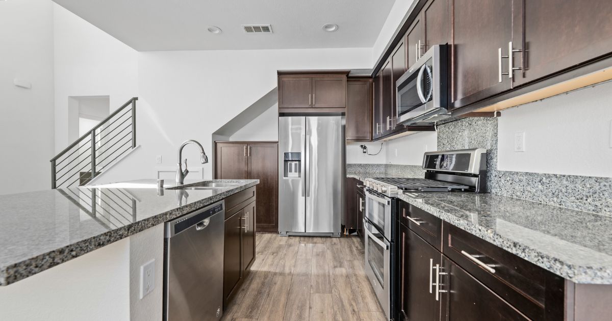 Kitchen in a Chula Vista townhome with granite countertops, dark wood cabinets, stainless steel appliances, and a center island.