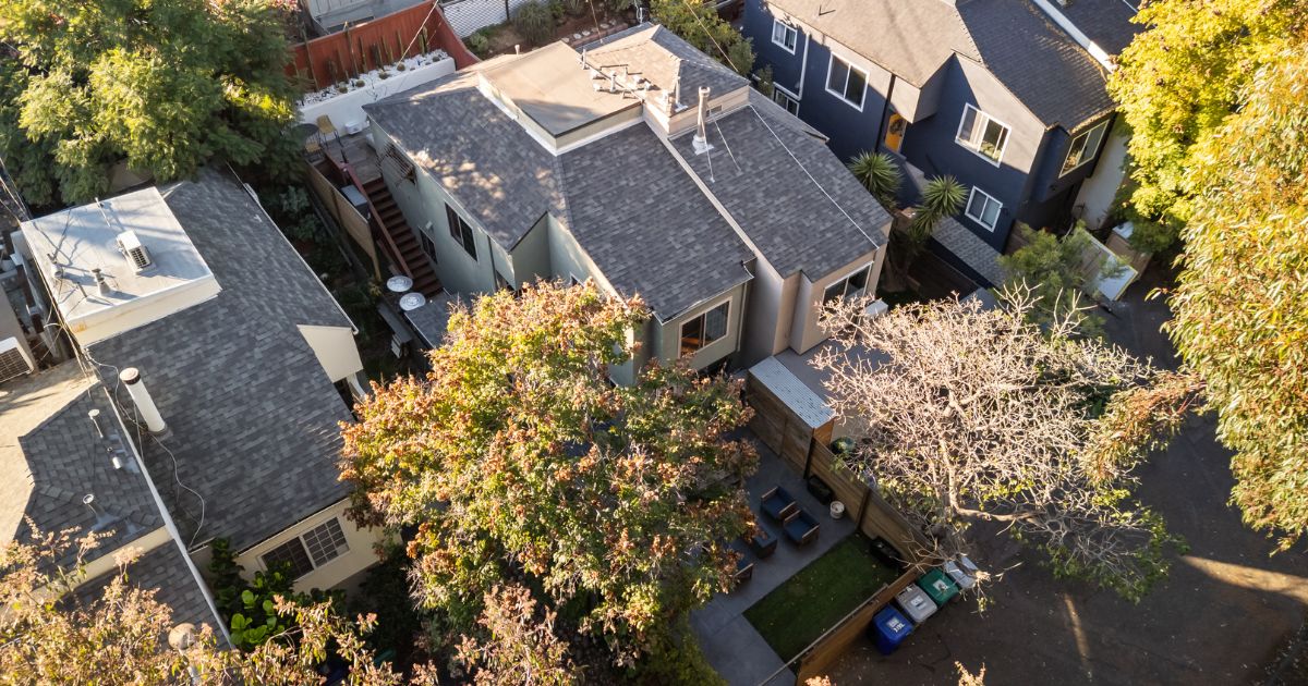 Aerial view of a San Diego home and neighboring properties surrounded by mature trees