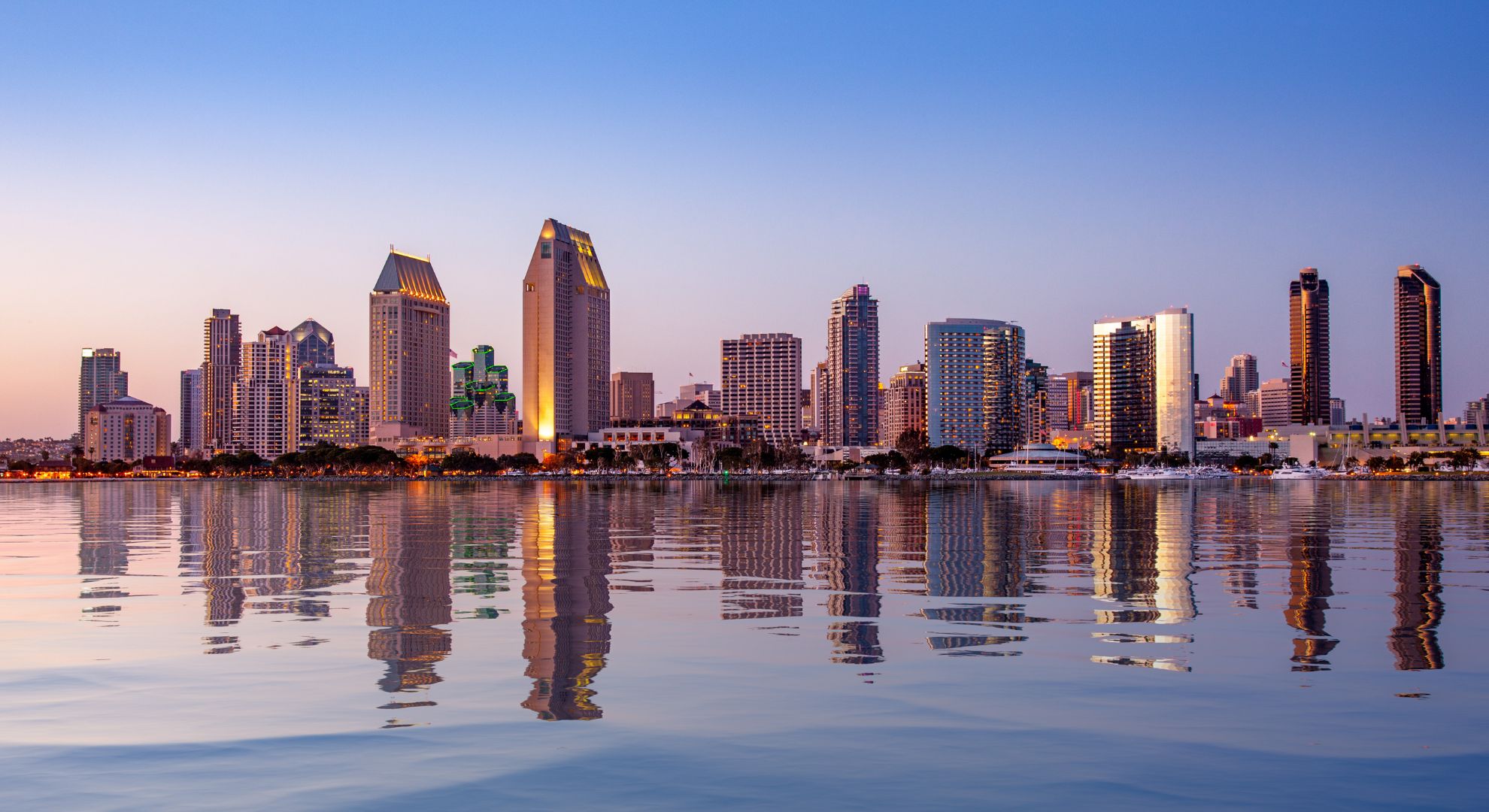 Downtown San Diego skyline at dusk reflected in the calm water of San Diego Bay
